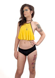 front view of Ally modeling a black tucking bikini with a yellow ruffle top