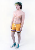 front view of Xander modeling the nonbinary pride boardshort when they were a size 32