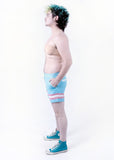 side view of Xander modeling the trans pride boardshort when they were a size 32
