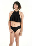 front side view of Angel modeling the tucking bikini and ruffle top in black as a set
